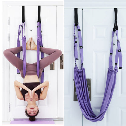 Person using a purple aerial yoga hammock against a white door.